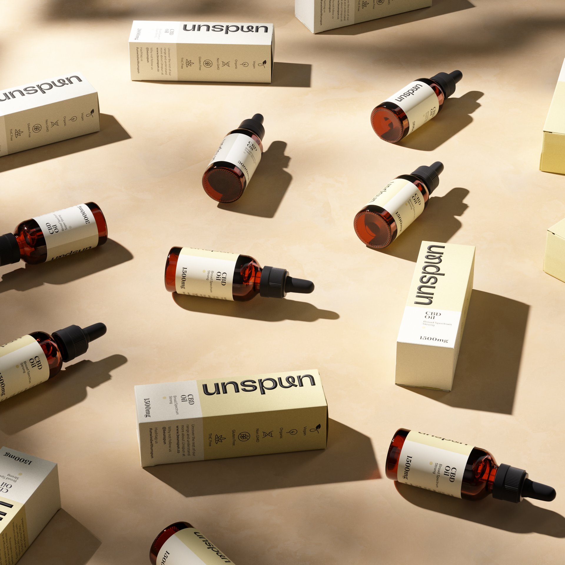  A display of Unspun CBD oil products cast in soft shadows. Multiple amber bottles with droppers labelled with the Unspun logo are interspersed with their corresponding white and beige boxes on a neutral background. The boxes are marked with product information and indicating 1500mg of CBD in a 30ml bottle.